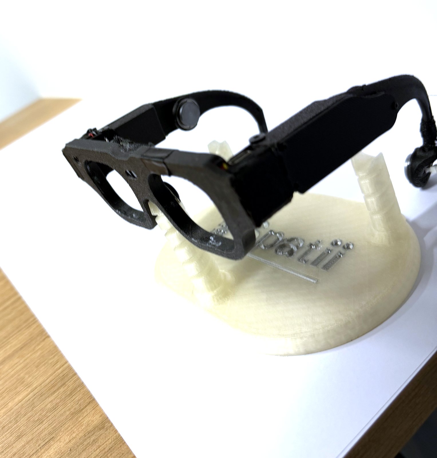 Photograph of the revision 4 prototype from the side, showing the temple arm electronics, the round bone-conduction transducer pads, and exposed development wiring.